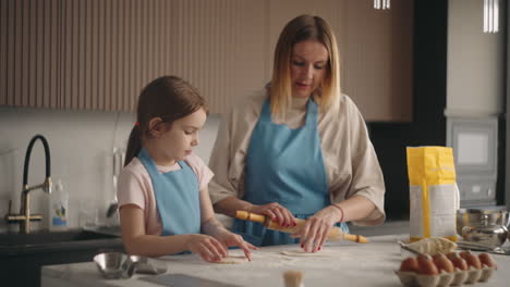 mother-and-daughter-are-cooking-cake-or-buns-in-home-kitchen-woman-is-teaching-child-to-cook